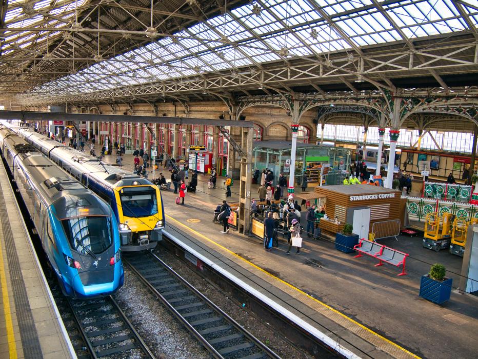 Two trains at platforms in Preston Station in the north west of England in the UK. The architecture of the roof is visible.